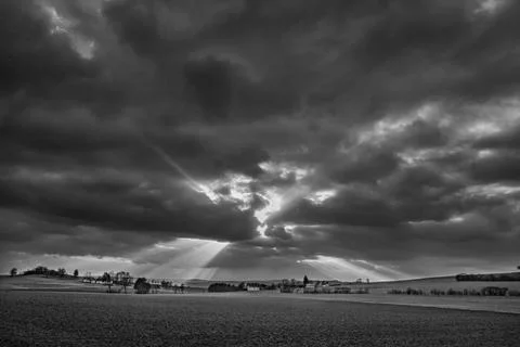 The sun's rays pierce the clouds over the agricultural field Stock Photos