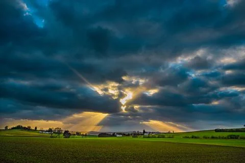 The sun's rays pierce the clouds over the agricultural field Stock Photos