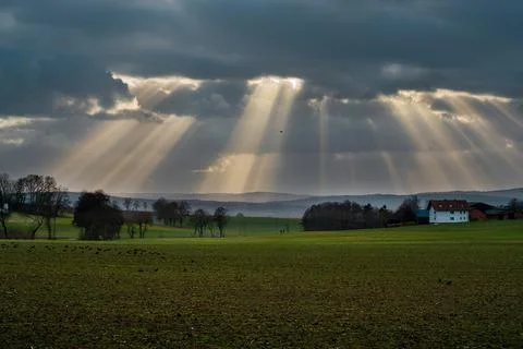 The sun's rays pierce the clouds over the agricultural field Stock Photos