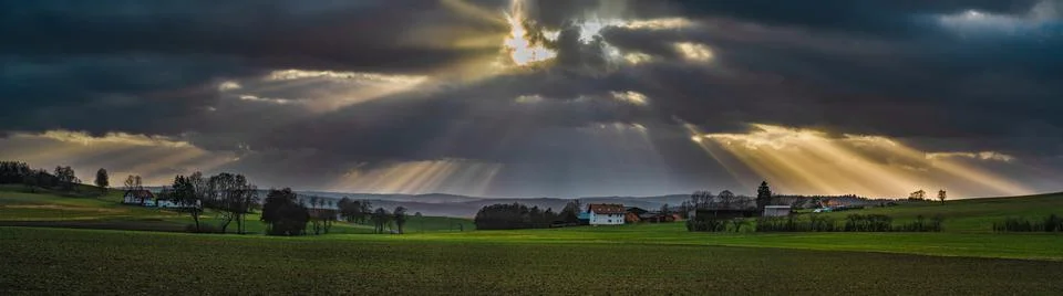 The sun's rays pierce the clouds over the agricultural field Stock Photos