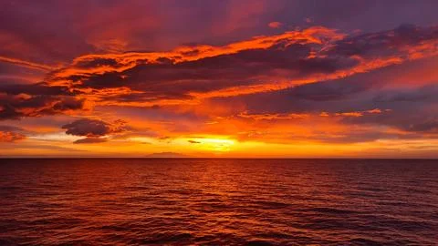 The sun's rays from the setting sun painted the clouds and the sea with sca.. Stock Photos