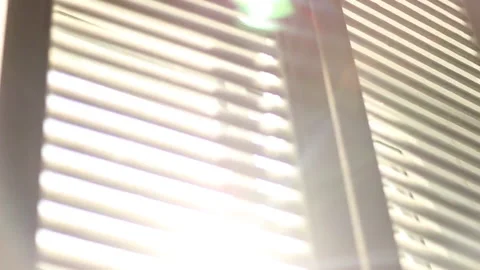 The sun's rays shimmer in the blinds close up tilt shot Stock Footage 202212837