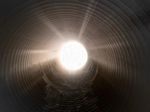 The sun's rays shine at the end of a large pipe. Stock-Fotos