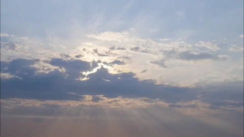 Sun's rays shine through the clouds floating across the blue sky. Stock Footage 164782784