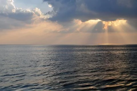 The sun's rays through the clouds above the sea. Stock Photos