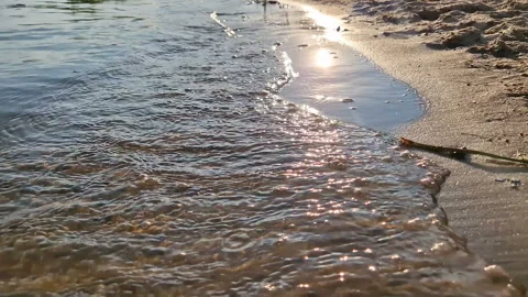 The sun's reflection in the water. Sandy beach with waves. Stock Footage 261146459