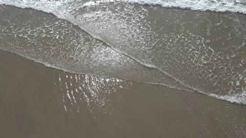 The suns reflection in the wet sand, as ￼shallow waves role in￼ on the beach￼ Stock Footage 121321859