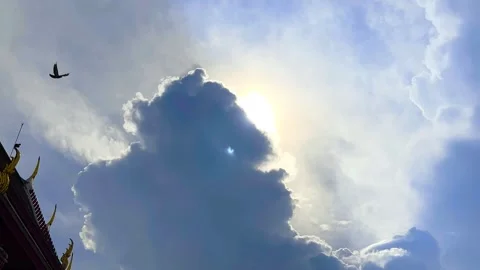 The Sun's Shining Behind Big Cloud, Bird on Roof of Temple on Sky with Bird Fly Stock Footage 328358245