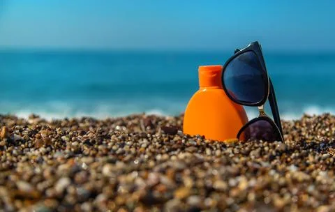 Sunscreen and glasses on the beach. Selective focus. Stock Photos
