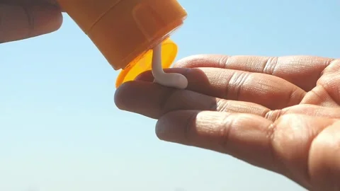 Sunscreen being applied to hand on sunny day, showing product for skin prot.. Video stock 332744651