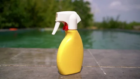 Sunscreen Bottle Rests on the Edge of the Pool Stock Footage 343047821