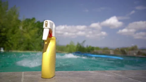 Sunscreen Bottle Stands by Pool as Boy Jumps In Stock Footage 345618413