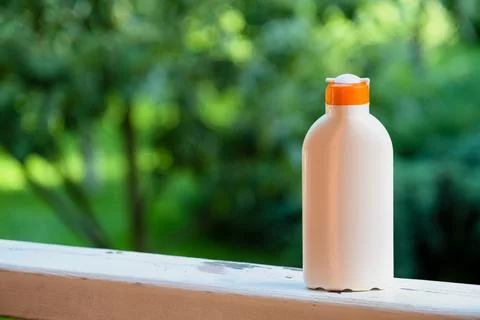 Sunscreen. Empty cream packaging template on greenery background. Stock Photos