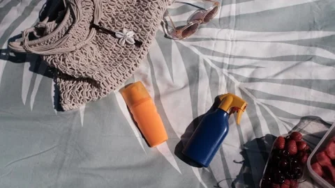 Sunscreen falling on beach towel, top view Stock Footage 313290916