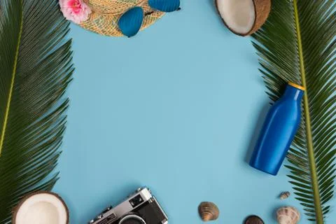 Sunscreen, glasses, hat on blue background, top view. Stock Photos