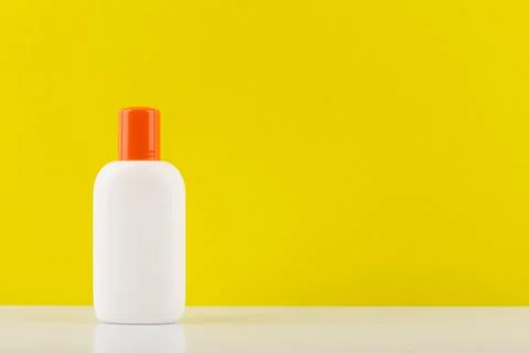 Sunscreen lotion for safe tanning on white table against yellow background with Stock Photos