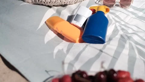 Sunscreen set on towel with blurred image of fruits in foreground Stock Footage 313290740