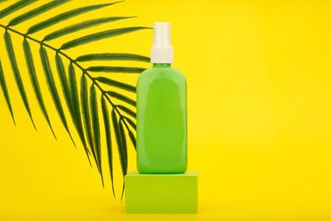 Sunscreen spray with Spf factor in green tube on green podium against yellow Stock Photos