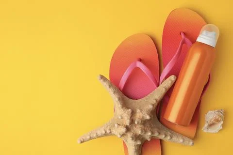 Sunscreen, starfish, shell and flip flops on orange background, flat lay wi.. Foto stock