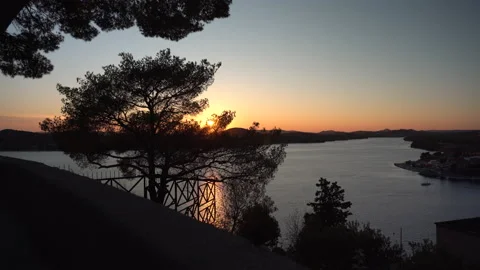 Sunset above the hills seen through the tree branches in Sibenik, Croatia - 4K Video stock 178482406
