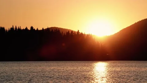 Sunset above mountain range with pine trees. Lake waves in nearground. Stock Footage