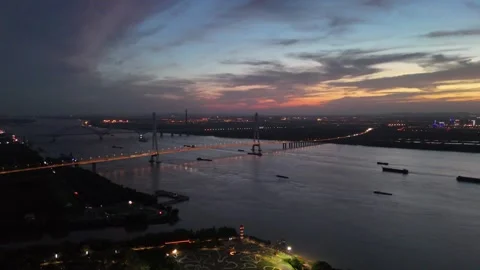 Sunset aerial over cable stayed bridge and river traffic in China Stock Footage 337754384