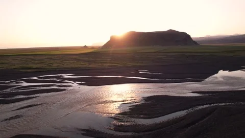Sunset Aerial Sun flare Over Rock Mountain With River Braids In Foreground Stock Footage 256713451