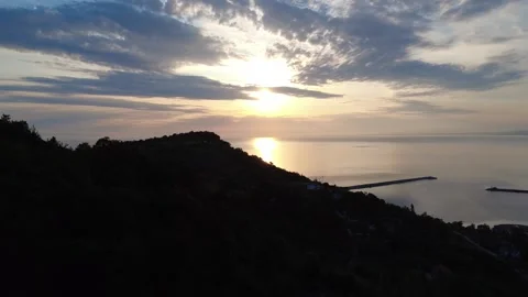 Sunset Aerial View Over Forested Coastline and Calm Sea – 4K Drone Footage 動画素材 311649304