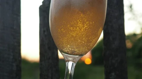 At sunset, after work, a man pours beer into a glass glass. cool in summer. 4K Stock Footage 134900665