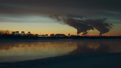 At sunset, against the backdrop of beautiful river, there is city with factories Stock Footage 113821904