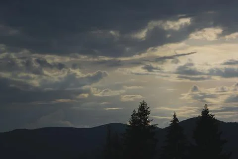 Sunset and clouds on a dark background of mountains Stock Photos