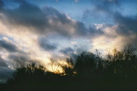 Sunset and clouds over forest create a peaceful setting at dusk Stock Photos