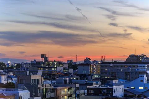 Sunset and clouds over lights of sprawling residential neighborhood Stock Photos