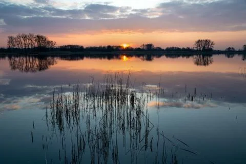 Sunset and clouds over a quiet lake with reeds Stock Photos