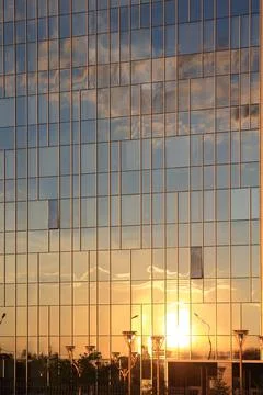 Sunset and clouds reflected in the glass facade of a skyscraper. Stock Photos