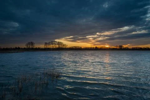 Sunset and dark clouds over the lake with reeds Stock Photos