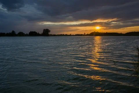 Sunset and dark clouds over the lake Stock Photos