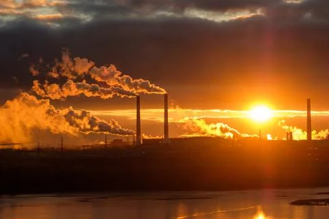 Sunset and evening clouds against the backdrop of factory smoking chimneys Stock Photos