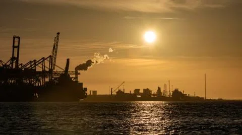 Sunset and gradient blue sky on the cranes loading containers at the biggest  Фото