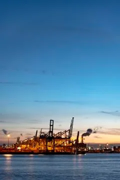 Sunset and gradient blue sky on the cranes loading containers at the biggest  库存照片