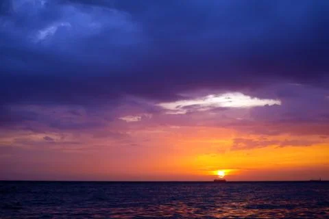 Sunset and ship on horizontal ocean water surface colorful cloud sky 写真素材