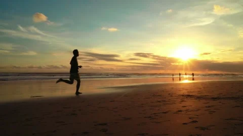 Sunset on Bali beach, man runs towards the sun Stock-Footage 65409658