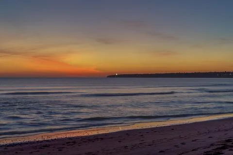 Sunset at the beach at Albufeira  with calm waves and distant lights from the Stock Photos