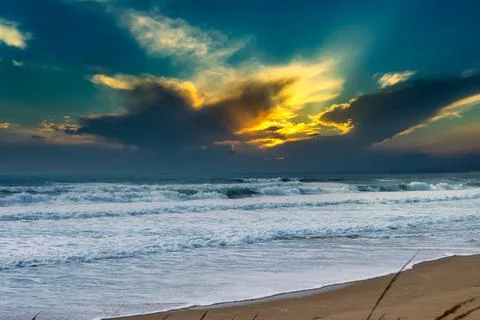 Sunset beach behind beautiful dramatic clouds Stock Photos