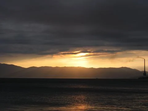 Sunset on the beach behind stormy clouds Stock Photos