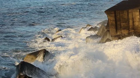 Sunset at the beach, big foamy waves crashing against the rocks on the shore Stock Footage 155791925