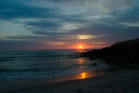 Sunset on the beach with clouds in the sky in blue and red colors Stock Photos
