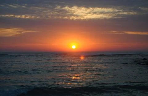 Sunset on the beach with clouds in the sky Stock Photos