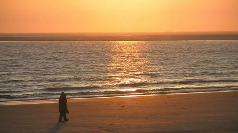 Sunset at beach, couple walking by Stock Footage 708678