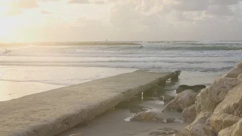 Sunset on the beach - dock in foreground - surfers in background Stock Footage 100708476